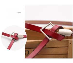 Detail showing red leather belt tie technique with a square matte silver buckle