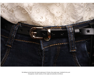Detail of black leather belt with star-shaped cutouts and golden buckle on denim jeans