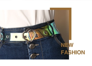 Nahaufnahme eines holografischen PVC-Gürtels mit silberner herzförmiger Schnalle auf Jeans