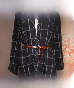 Detail of brown leather skinny belt with silver diamond buckle tied on a plaid shirt