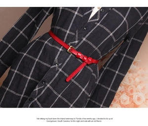 Close-up of red embossed leather belt with gold buckle on a black and white checkered dress