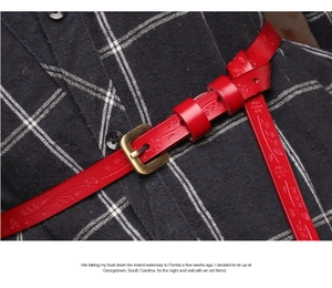 Detail of red leather belt with floral embossing and vintage gold buckle on a check shirt