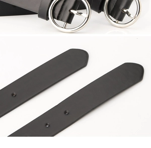 Detail view of black faux leather belt with a round silver buckle and textured strap surface