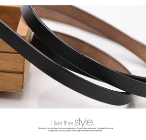 Detail of slim black leather belt showing textured finish and brown underside leather