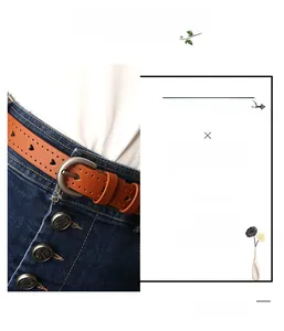 Dettaglio di una cintura in pelle marrone con cuori traforati e fibbia in metallo su denim