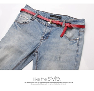 Detail of red embossed leather belt with vintage gold buckle on blue jeans