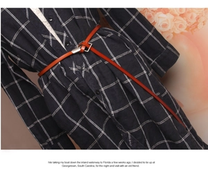 Detail of slim brown leather belt tied over a black and white plaid shirt dress