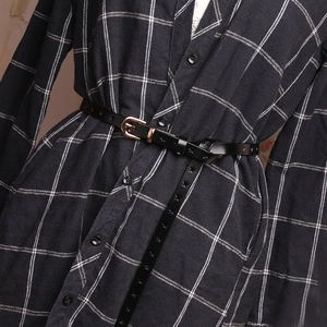 Women's black leather belt with star cut-outs and golden buckle over a checkered shirt