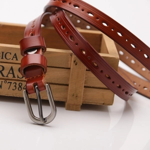 Brown leather belt for women with decorative cutouts and silver metal buckle in a still life view