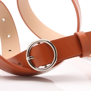 Brown leather belt with round silver metal buckle and adjustable circular holes on white background