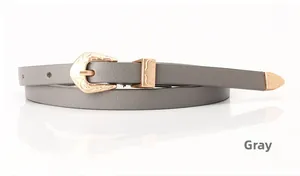 Detail of grey skinny belt with Western style floral carved buckle and gold metal tip