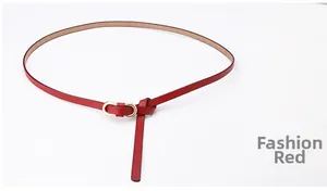 Detail of red textured leather slim belt featuring a gold oval metal buckle
