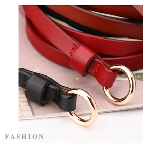 Détail de la ceinture fine en cuir avec boucle dorée ronde et coutures précises