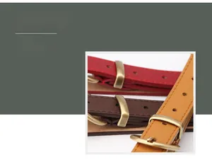 Detail view of thin faux leather belts in red, brown, and yellow with antique metal buckles