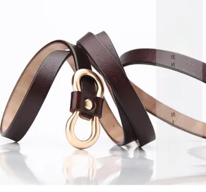 Close-up of slim leather belt with a golden matte double-ring buckle and fine texture