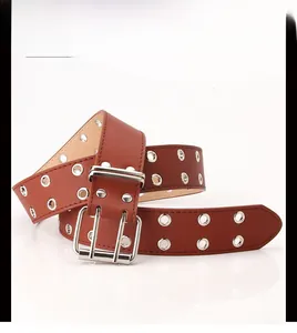 Détail d'une ceinture en cuir marron avec double rangée d'œillets argentés et boucle