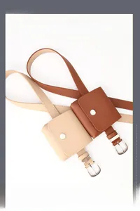 Detail view of mini PU leather belt bags in cream and brown with silver metal buckles
