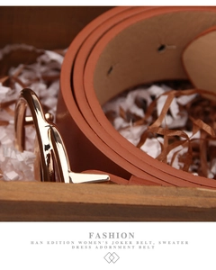 Close-up of brown leather belt with gold round buckle in a decorative wooden gift box