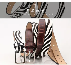 Detail view of stylish zebra stripe and brown crocodile pattern belts with silver buckles