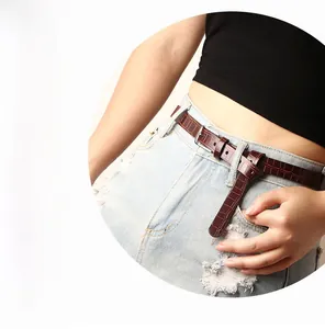 Detail of dark brown crocodile pattern skinny belt with silver buckle on blue jeans