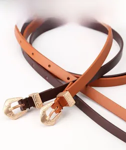 Detail of slim leather belts with vintage engraved gold buckles in coffee and tan colors