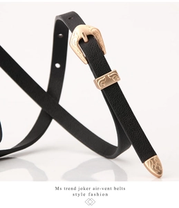 Close-up of black leather slim belt with vintage rose gold engraved buckle and tip
