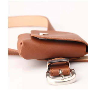 Close-up of brown leather waist bag with silver buckle and fine litchi grain texture