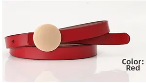 Close-up of elegant red leather belt with round gold metal buckle on white background