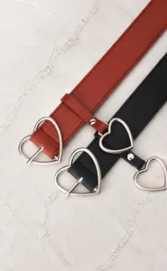 Detail of slim black and brown belts featuring heart-shaped silver metal pin buckles