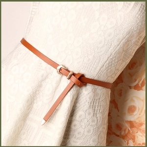 Caramel thin leather belt with gold floral buckle on a white lace dress