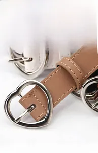 Detail showing heart-shaped alloy buckles on white and brown women's leather belts
