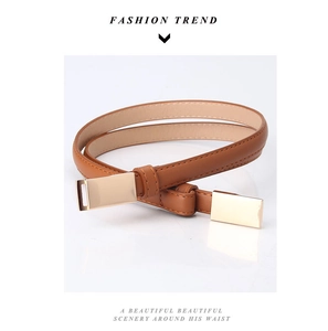 Détail d'une ceinture fine marron caramel avec surpiqûres et embout en métal doré