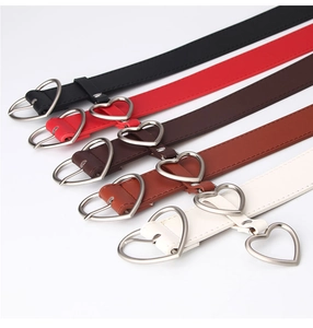 Detail of five slim women belts in various colors featuring heart-shaped silver buckles