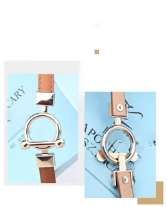 Detail of adjustable brown leather belt with gold metal round buckle and T-bar closure
