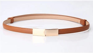 Détail d'une ceinture fine en cuir camel avec boucle rectangulaire en métal doré poli