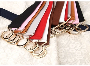 Detail of colorful elastic waist belts with interlocking golden metal ring buckles