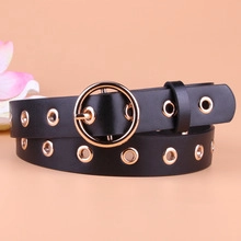 Détail de la ceinture en cuir noir avec boucle dorée ronde et œillets métalliques décoratifs