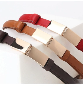 Détail de trois ceintures fines en cuir avec boucles rectangulaires dorées en rouge et marron
