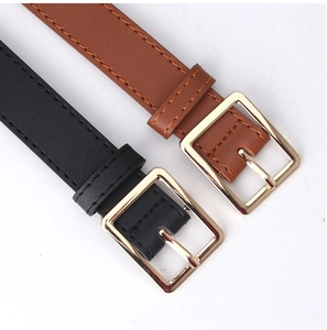 Close-up of black and dark brown slim leather belts with golden rectangular metal buckles