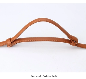 Détail d'une ceinture en cuir marron caramel avec surpiqûres orange et texture souple