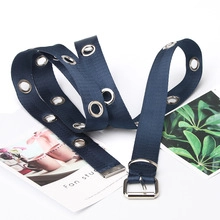 Détail de la ceinture en toile bleu marine avec œillets métalliques et boucle ardillon carrée