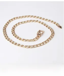 Détail d'une ceinture chaîne dorée à maillons cubains avec pendentif cœur et boucle carrée