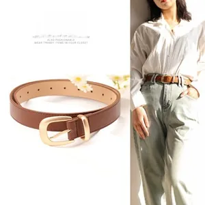 Vue détaillée d'une ceinture fine en cuir marron avec boucle dorée mate sur chemise