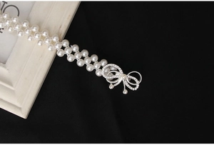 Detail der eleganten zweireihigen Perlen-Taillenkette mit Strass-Schleife auf Samt