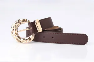 Close-up of brown leather belt with large textured gold circular metal buckle