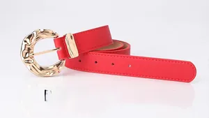 Detail of red leather belt featuring a designer golden circular hammered metal buckle
