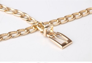 Détail d'une ceinture chaîne dorée avec boucle polie et maillons plats métalliques