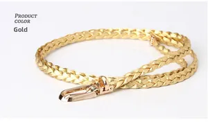 Detail view of a thin braided gold waist belt featuring a sleek metal U-shaped buckle