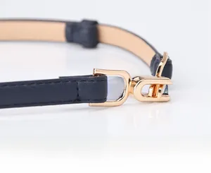 Detail of navy blue leather skinny belt featuring elegant gold horseshoe buckle closure