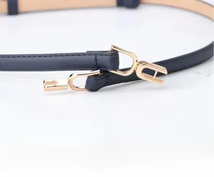 Close-up of slim dark blue leather belt for women with elegant golden metal buckle